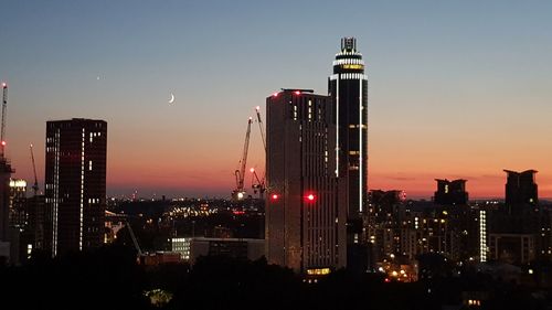 Illuminated buildings in city against sky at night