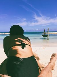 Low section of man sitting on beach