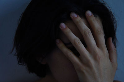 Close-up of woman with face covered by hand