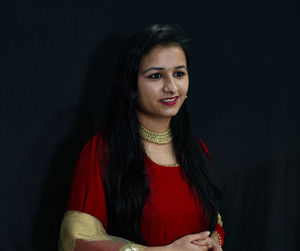 Portrait of smiling young woman against black background