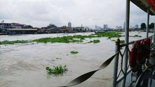 Scenic view of river by city against sky