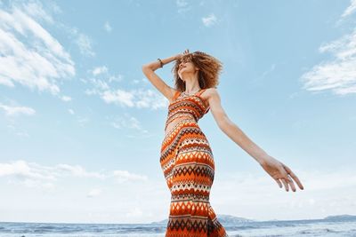 Low angle view of woman standing at beach against sky