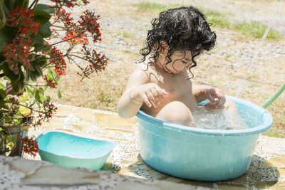 Happy girl playing in bucket with water