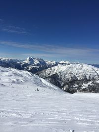 Scenic view of snowcapped mountains against blue sky