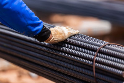 Cropped hand touching rods at construction site