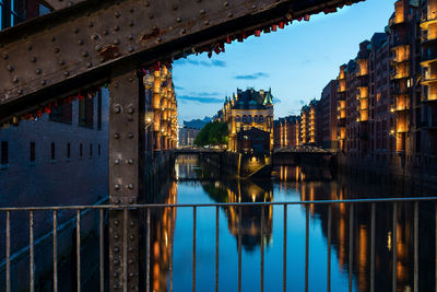 Bridge over river by buildings against sky in city