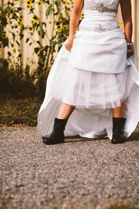 Low section of bride in wedding dress standing on road