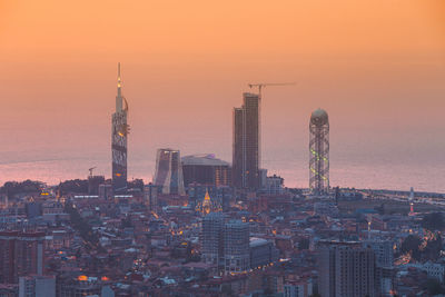 Illuminated cityscape against sky during sunset