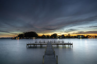 Pier over lake against sky at sunset