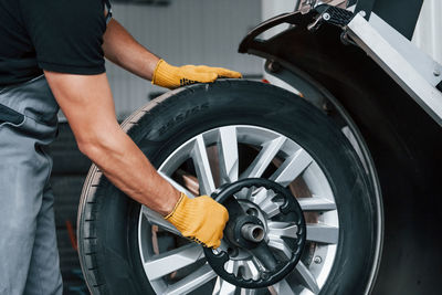 Taking the wheel. man in uniform is working in the auto service.