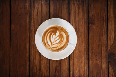 Latte art coffee on wooden table in coffee shop