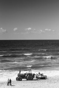 Tractor on shore at beach against sky