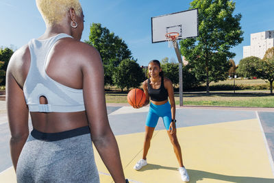 Sportswoman playing with basketball friend in court