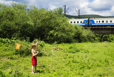 Boy standing in grass by railroad track