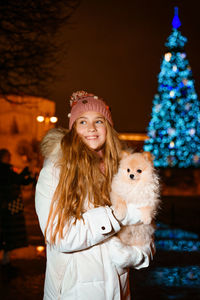 Beautiful teenage girl plays and has fun with her spitz dog, in evening on city