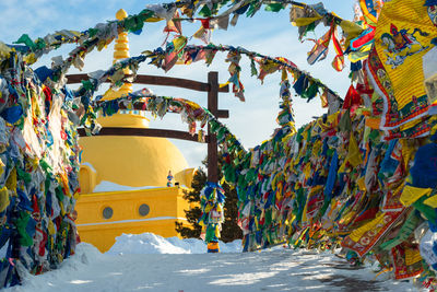 Prayer flags with tibetan mantras in wind at snowy temple complex, asian culture at local monastery