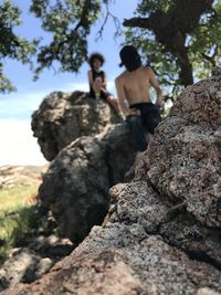 Low angle view of people on rock against sky