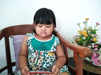 Full length of cute girl sitting on chair