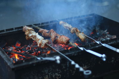 Meat on barbecue grill against sky at night