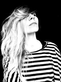 Portrait of smiling young woman against black background