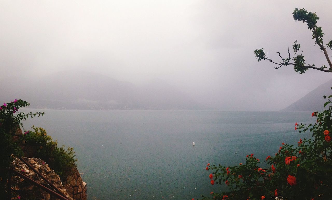 SCENIC VIEW OF SEA BY MOUNTAINS IN FOGGY WEATHER