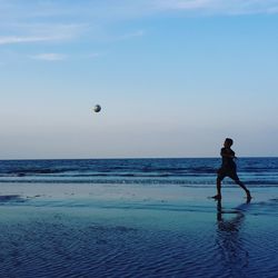 Boy playing soccer at beach