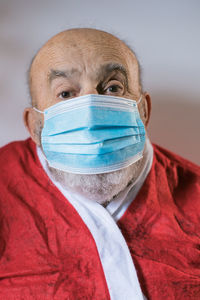 Close-up portrait of senior man wearing mask against wall