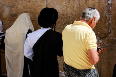 Rear view of men standing against wailing wall