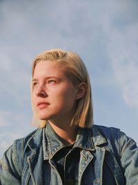 Portrait of young woman looking away against sky