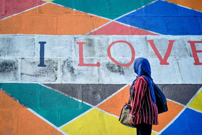 Woman standing by graffiti wall
