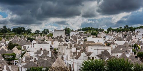 High angle view of trullos in alberobello town against cloudy sky