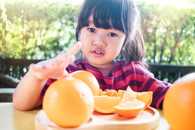 Portrait of girl having orange fruits