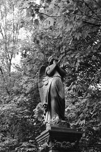 Rear view of man standing by statue in forest