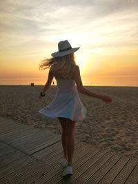 Rear view of woman looking at sea during sunset