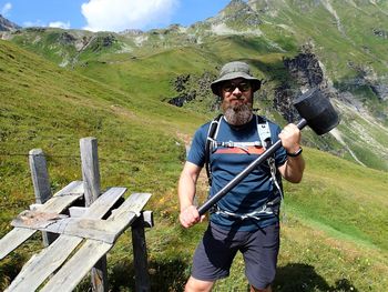 Portrait of mature man holding hammer while standing on mountain