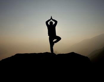 Silhouette of woman against sky at sunset