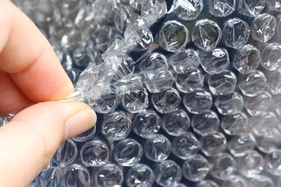 Close-up of cropped hand popping bubble wrap