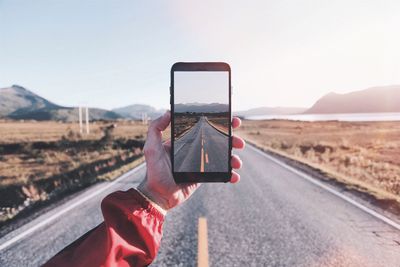 Close-up of hand holding smart phone against clear sky