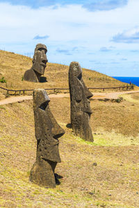 Stone sculptures on landscape against sky