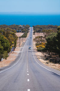 Road passing through city against sky