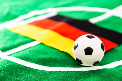 Close-up of small soccer ball with flag on green textile