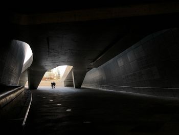 Rear view of silhouette person walking in illuminated tunnel