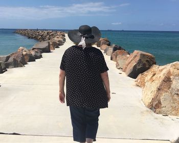 Rear view of woman walking on pier at sea