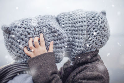 Rear view of sibling embracing while standing by lake during winter