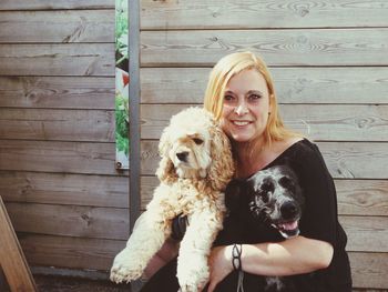 Smiling woman carrying dogs while standing against wall