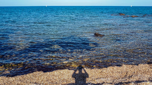 High angle view of sea shore against sky with shadow selfie