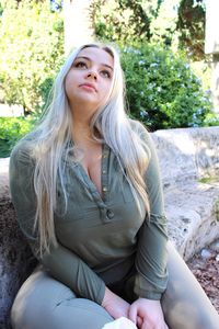 Beautiful young woman looking up while sitting at park