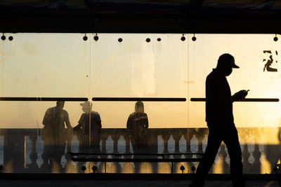 Silhouette people standing by railing