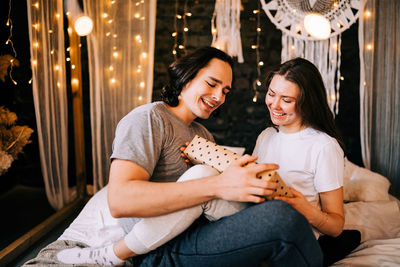 Young man and woman romantic couple couple hug and giving gift box present