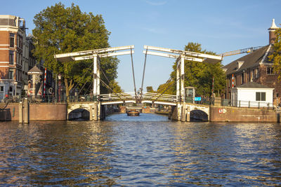 Bridge over river in city against sky